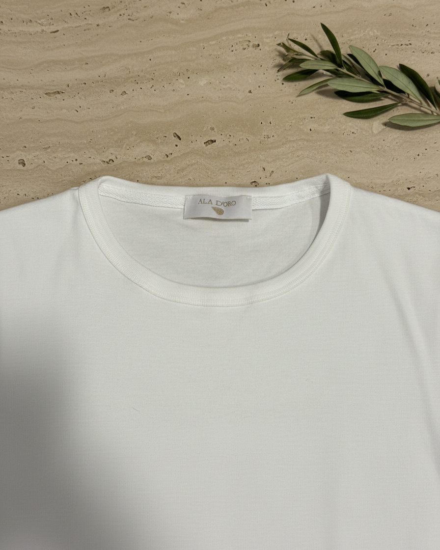 White t-shirt with a brand label on a wooden surface with a branch.